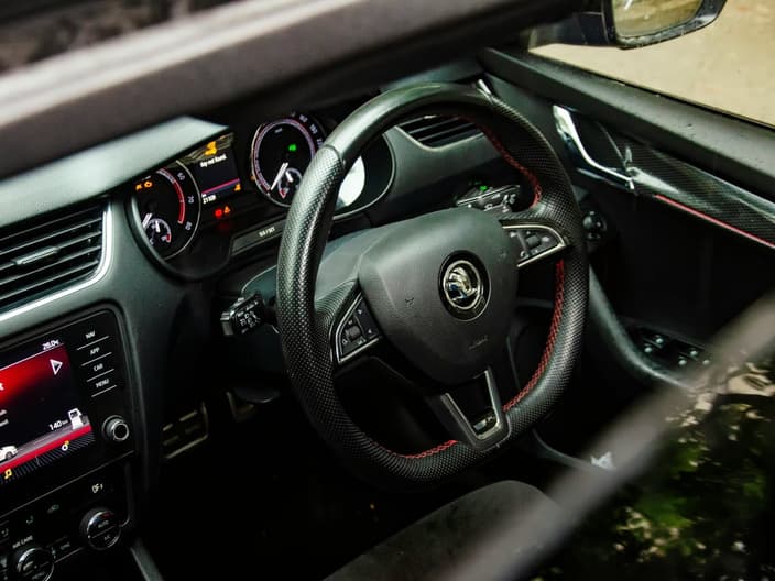 Interiér vozu Škoda se sportovním volantem a rozsvícenou varovnou kontrolkou na palubní desce, která signalizuje potřebu diagnostiky elektroniky.
