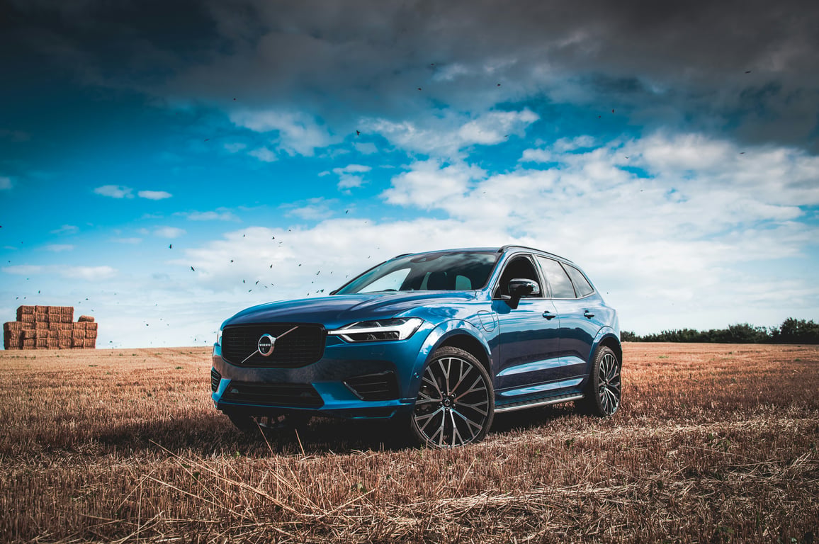 Синий роскошный внедорожник Volvo XC60 в поле, символизирующий нашу приверженность безопасности и надёжности через экспертное обслуживание Volvo.