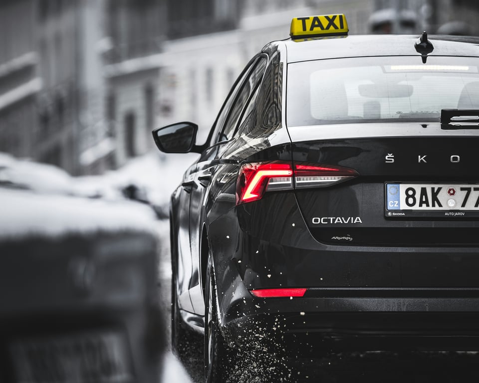 Чёрное такси Škoda Octavia в городе, представляющее наши надёжные услуги по техническому обслуживанию коммерческих и корпоративных автомобилей.