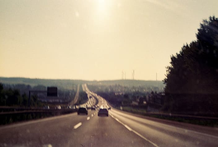 Auto na rozpálené dálnici v letním vedru, ilustrující typické letní poruchy jako přehřívání motoru a problémy s pneumatikami.