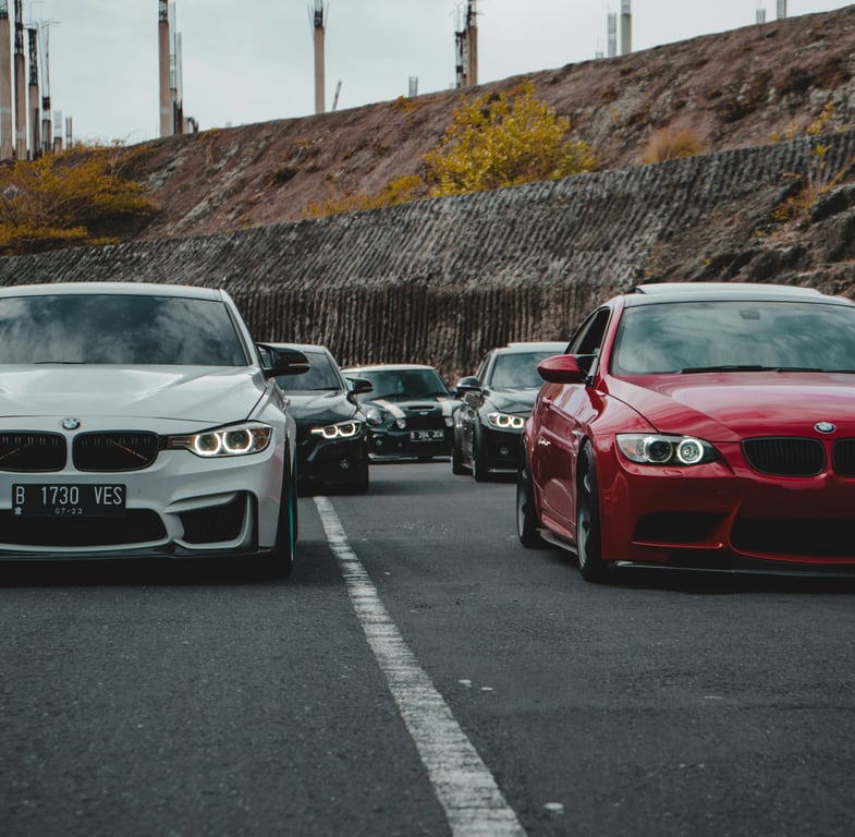 Výkonné sedany BMW M3 v bílé a červené barvě, představující naši odbornost v oblasti tuningu a oprav špičkových sportovních vozů.