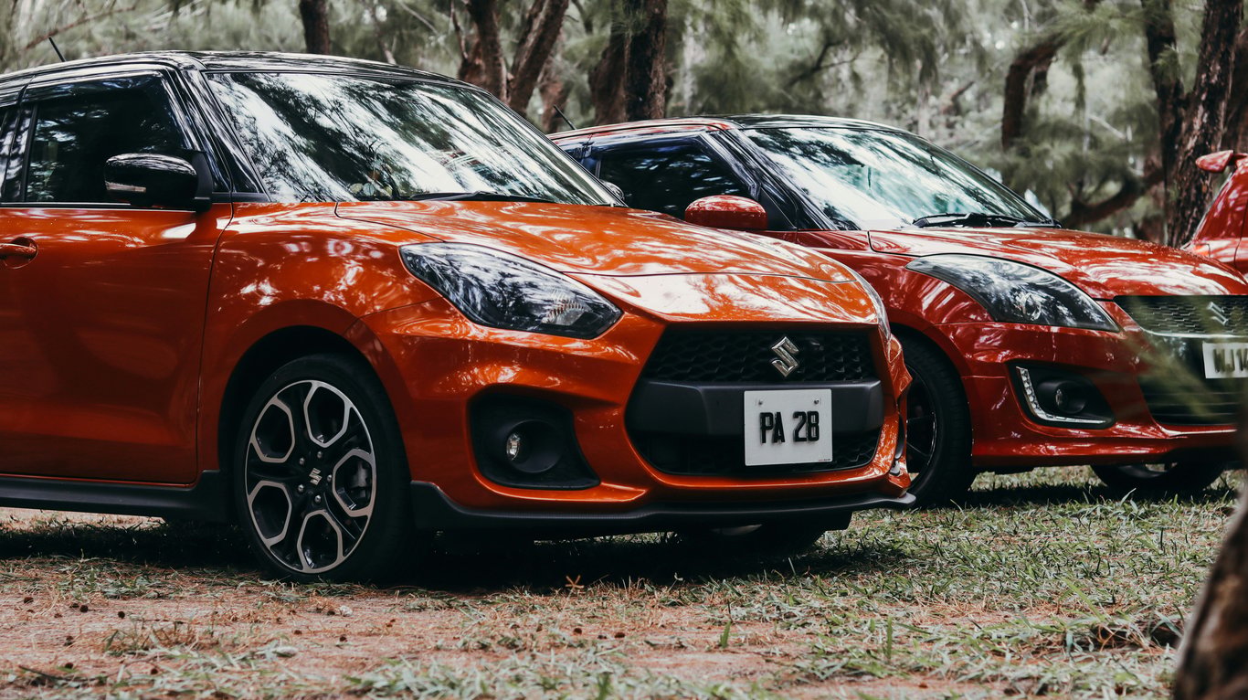 Oranžový a červený kompaktní vůz Suzuki Swift Sport, představující náš kvalitní servis pro zábavné a úsporné hatchbacky.