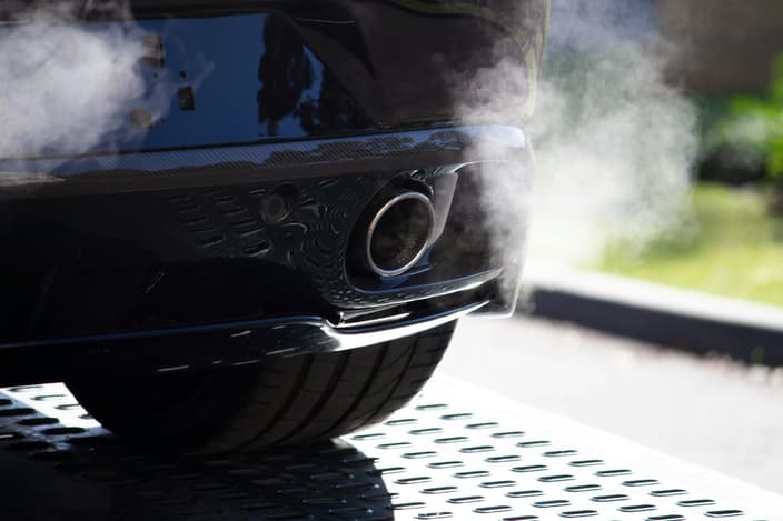 Detailní záběr na výfuk automobilu, ze kterého vychází bílý kouř, což signalizuje možnou poruchu motoru nebo problém s emisemi.