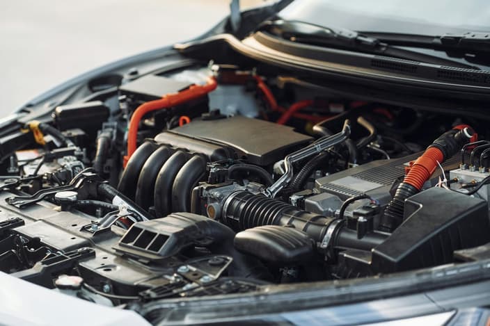 Motorový prostor moderního automobilu s otevřenou kapotou a viditelnými komponenty motoru.