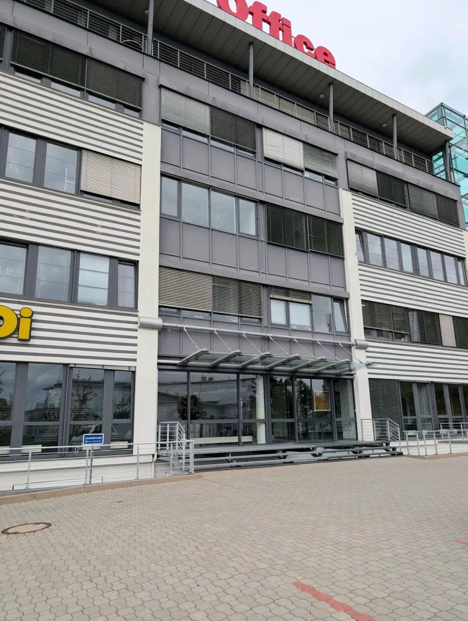 The entrance of the building in Prague 5-Jinonice where EVEREST Solutions has its office: a glazed entrance under a canopy