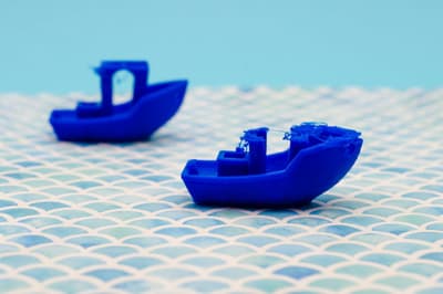 Two blue 3D printed boat models on a patterned surface as an example of a successful first print