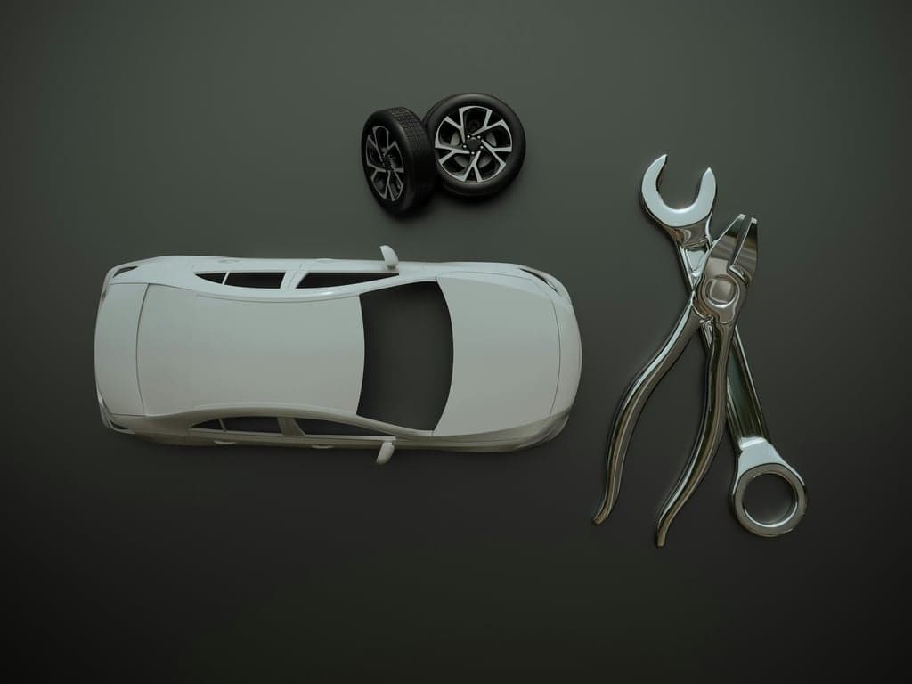 3D printed parts for the automotive industry, including covers and prototypes, lying next to a wrench.